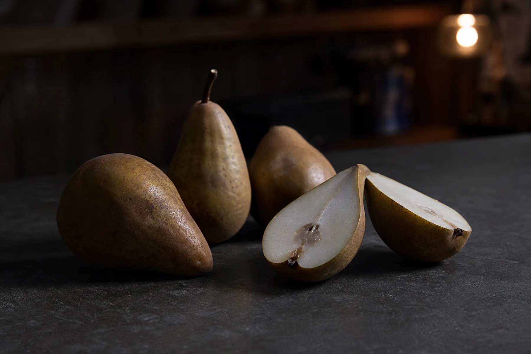 Small hard pears, some cut in half, showing dense pale flesh and a gritty texture.